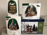Four Department 56 Dickens Village buildings in their original boxes showing the four different collectible buildings.