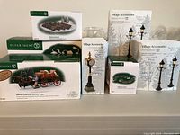 Lot showing all boxed Department 56 accessories including lamps, landscaping bases, and the delivery wagon.