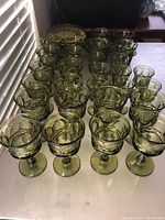 Full view of the collection showing multiple rows of olive green glassware items arranged by type.