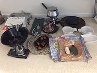 Photo showing overall kitchenware lot including fondue pot, forks, bowls, plates, placemats, napkin rings, and trays.