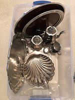 Photo of all silverplate pieces arranged in a plastic bin showing trays, pots, and serving dishes.