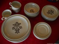Photo showing all components of the dish set: six dinner plates, six bowls stacked, six cups, and six saucer plates all decorated with a brown floral pattern on a beige background.