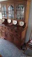 View of antique wooden china cabinet with glass display top and multiple drawers and doors for storage.