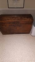 Full view of antique wooden steamer trunk showing wood grain and dome-shaped lid.