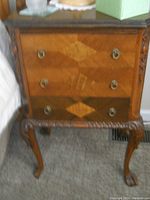 Wooden night stand with three drawers featuring diamond-shaped inlay decoration and carved cabriole legs. Shows visible wear, needs restoration.