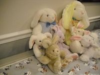 Seven Easter bunny plush toys arranged on a surface with patterned fabric backdrop