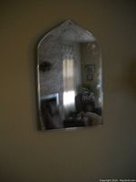 Photo of an arched vintage mirror showing aged and distressed reflective glass.
