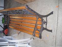 Wood outdoor bench showing wooden slats, metal frame, and armrest detail.