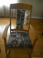 Front view of wooden rocking chair showing natural wood frame and Route 66 themed upholstered seat and backrest.