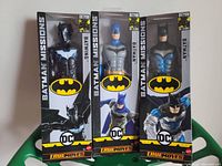 Front view of three sealed Batman Missions 12-inch action figure boxes showing the figures inside with distinctive Batman costumes and branding.
