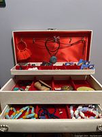 Full image of jewelry box open, showing hooks for necklaces and organized compartments with jewelry items inside.