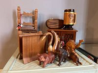 Photo showing most lot items including the miniature chair, music box, wooden mug, carved animals, and wooden box with lattice door.