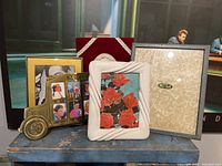 Front view showing all 5 photo frames together including ceramic, brass bus, velvet, white and gold, and leather frames