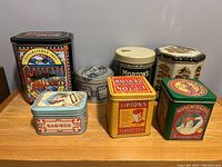 Front view of all 7 tins showing their sizes, shapes and branding
