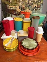 Full assortment of Tupperware containers and accessories arranged on table showing variety of colors and shapes.