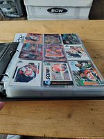 Open binder showing several NASCAR trading cards in plastic sleeves, arranged in a 3x3 grid per page.