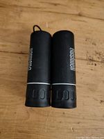 Top view of black Bushnell compact binoculars folded, showing textured rubber grips and logo.