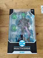 Front view of the DC Multiverse Blight action figure in retail packaging showing figure with green and purple coloration and translucent green accessories.