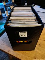 Photo of black short box filled with comics, showing the top edges of about 180 comics stored vertically inside.