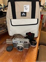 Overview of entire lot showing Canon camera, Nikon lens, carrying case, and insulated bag