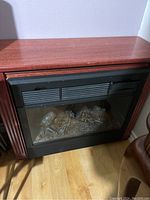Image of electric fireplace showing the front view with faux logs behind glass and wood finished frame.