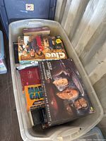Photo showing the assortment of board games including Clue, Magic Card Game, Star Trek The Next Generation Trivia, and others in a tote box.