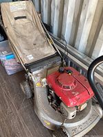 Full view of the Honda self propelled lawn mower showing the grass collection bag, engine, and wheels, confirming hydrostatic drive.