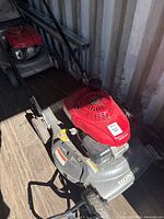 Side view photo of the full Honda gas lawnmower with handlebar and wheels visible.