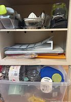 First photo showing baking utensils, tea kettle, graters, and other kitchen gadgets in clear plastic tote and shelves.