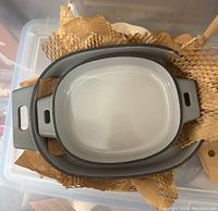 Top view of three gray oval Pampered Chef baking dishes nested inside one another with brown packing paper between.