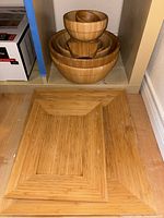 Two matching rectangular wooden trays placed side by side on the floor beneath the bowls.