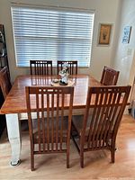 Overview photo showing the rectangular wood table with six matching chairs around it in a dining room.