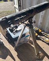 Full view of the Telstar 114AZ telescope mounted on tripod, showing black telescope tube with dust and signs of wear, finder scope attached, and altazimuth mount with adjustment knobs.