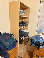Photo of one wooden shelving unit surrounded by bags and personal items showing height and shelf depth.