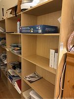 Photo showing three wooden shelving units with five shelves each, containing a few items but mostly empty.