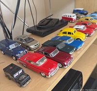 Photo showing multiple mini metal cars arranged on a shelf, showcasing various colors and styles.