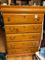 Front view of solid wood chest with five drawers and mixed round wooden and metal pull handles