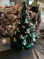 Front view of the green ceramic Christmas tree illuminated with multi-colored bulbs