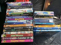 Photo showing a stack of DVDs including Frozen Sing Along, Shrek the Halls, Ratatouille, Mary Poppins, Ice Age, The Best Exotic Marigold Hotel, Country Calendar, and Imagine That.