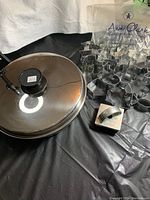 Photo showing the egg poacher/fry pan with glass lid and assorted metal cookie cutters arranged on a black surface.