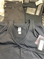 Two pairs of women's jeans and a black yoga top laid out, showing brand and size labels.