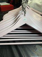 Full set of 22 light pink wooden hangers stacked together, all with metal hooks and matching bottom bars, shown from the top.