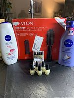 Revlon One-Step Ultra Styling Kit box with two brush heads, Nivea lotion and Nivea hair treatment bottles, four mini OPI Nail Envy bottles visible