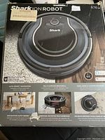 Front box view showing the Shark Ion Robot vacuum with features including auto-sense navigation, multi-surface brushroll, dual edge & corner brushes, and designed for pets.