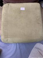 Top view of the square green velvet storage stool showing fabric texture and light wear.