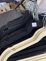 Photo showing black velvet hangers stacked together, close-up of hook tops and velvet texture