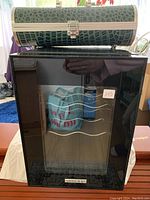 Front view of black Vissani wine cooler with glass door and faux crocodile bottle-shaped purse on top