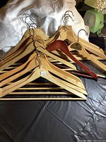 Group of 15 assorted wooden hangers laid out showing variety of styles and finishes including natural and dark wood.