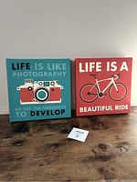 Front view of both inspirational square canvas pictures on wooden surface