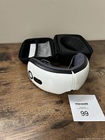 Eye massager device with visible controls, soft internal padding, and no box. Also shows auction tag number 99.